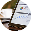 Photo of laptop screen showing data analytics with coffee cup in the background.